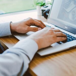 A man working on a laptop in a modern office setting.